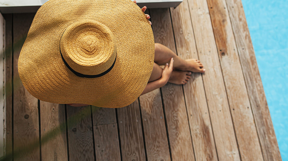 Mujer en borde de piscina, cubriéndose con sombrero