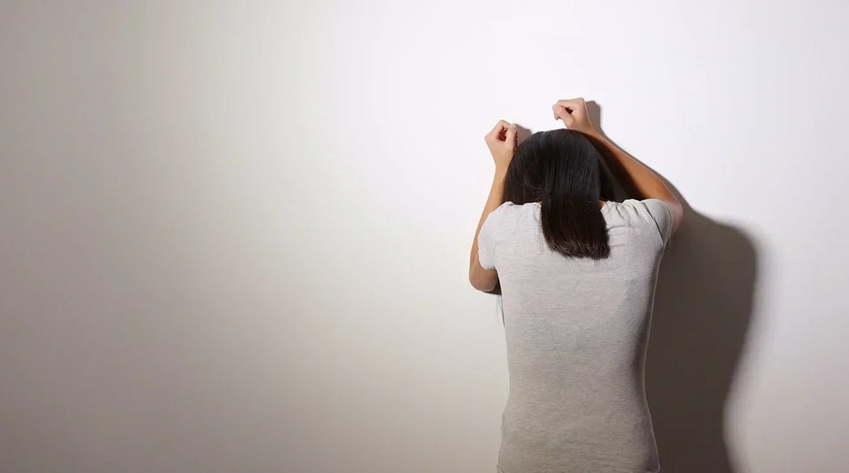 Mujer apoyada contra la pared, signos de estrés
